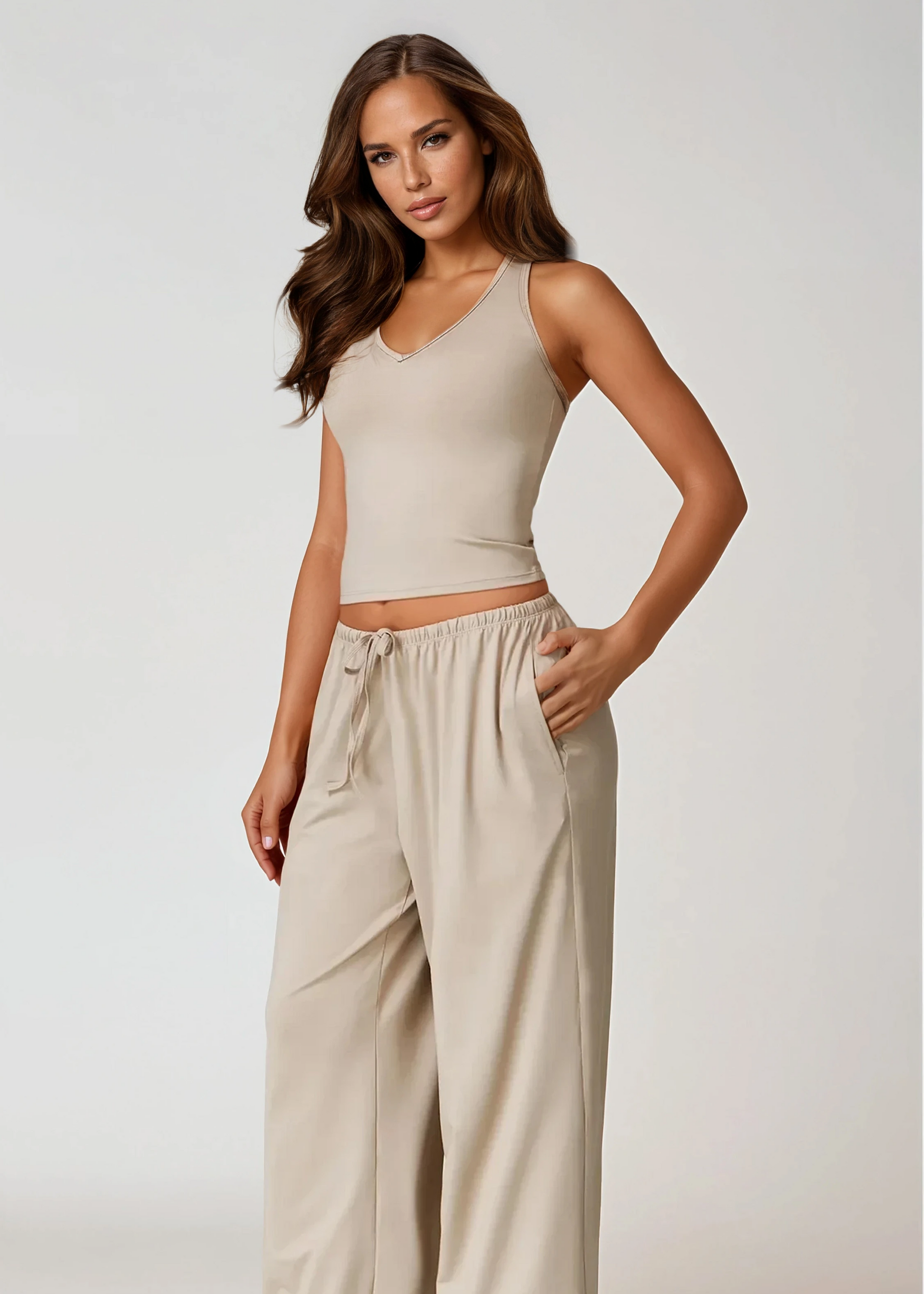 Woman wearing a beige tank top and wide-leg pants on a white background