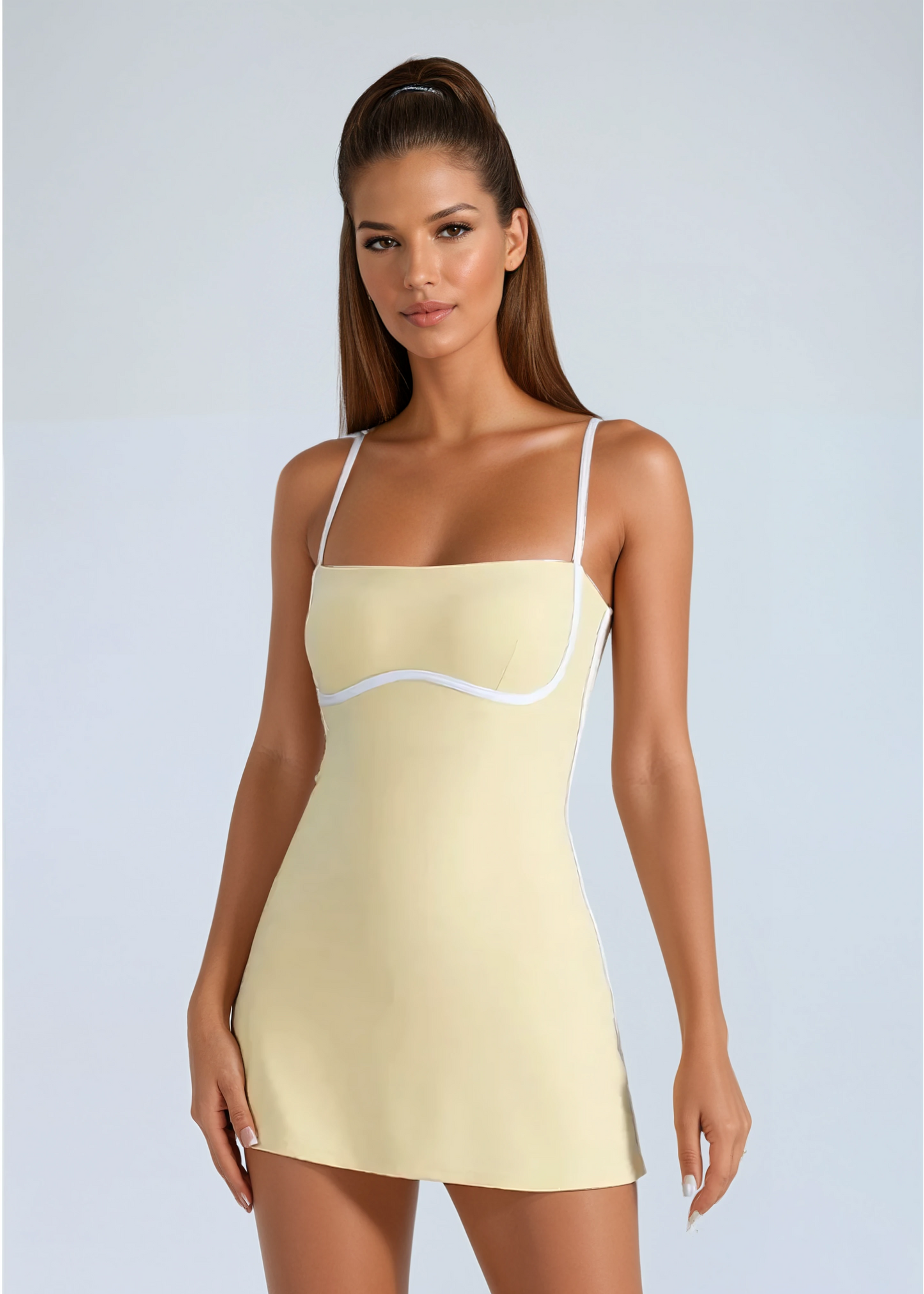 Woman wearing a light yellow slip dress with thin straps on a plain background