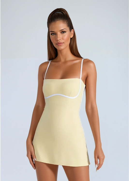 Woman wearing a light yellow slip dress with thin straps on a plain background